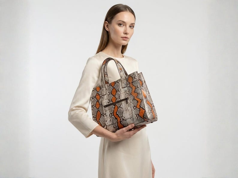 Elegant woman holding orange python snakeskin luxury tote bag