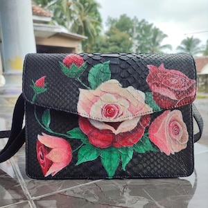 Bolso de piel de serpiente pintado a mano con flores rosas realizado por mujeres balinesas para apoyar a las mujeres en sus negocios