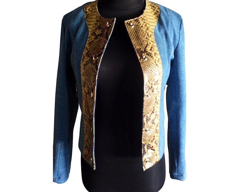 Op de afbeelding: Een blauwe blazer met een slangenhuidpatroon aan de voor- en achterkant. De blazer heeft een kraag en lange mouwen.