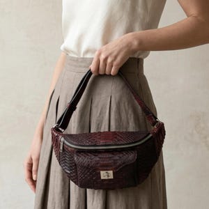 Może przedstawiać: Zestaw trzech ceramicznych kubków z nakrapianym, matowym wykończeniem. Kubki są w odcieniach kremu, jasnoszarym i ciemnoszarym. Każdy kubek ma prosty, minimalistyczny design i zaokrąglony uchwyt.