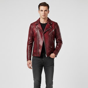 May include: A red leather jacket with a snakeskin pattern. The jacket has a zipper closure, a notched collar, and multiple pockets. The model is wearing a black shirt and dark gray jeans.