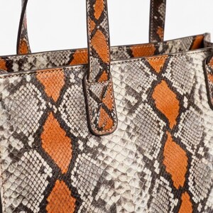 Close up detail of orange python snakeskin leather texture and stitching