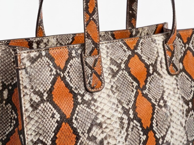 Close up detail of orange python snakeskin leather texture and stitching