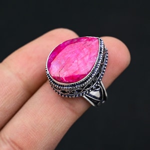 May include: A silver ring with a large, teardrop-shaped pink gemstone set in an ornate silver setting.