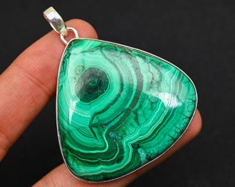 May include: A silver pendant featuring a green malachite gemstone with a swirling pattern. The pendant is in the shape of a triangle.