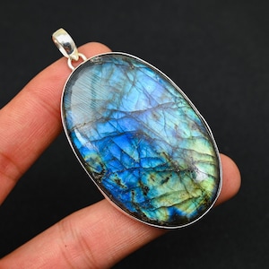 May include: A silver pendant featuring a large oval-shaped labradorite gemstone with iridescent blue, green, and black hues.