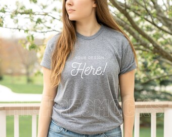 May include: A heather grey t-shirt with rolled up sleeves. The shirt has the text "YOUR DESIGN HERE!" printed on the front.