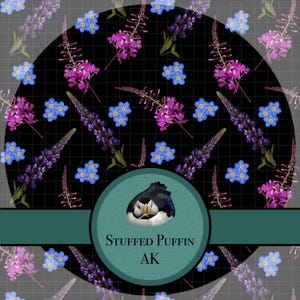 Peut inclure: Un motif circulaire avec une illustration de macareux dans un cercle turquoise, avec le texte "STUFFED PUFFIN AK". Le fond noir présente un motif floral de fleurs violettes et bleues, dont des lupins et des myosotis.