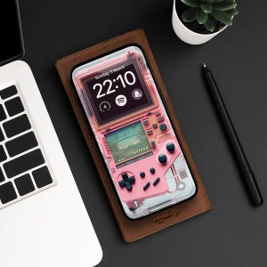 May include: A pink and black handheld game console with a clear plastic case. The screen displays the time, "Sunday, 3 March", and "22:10".