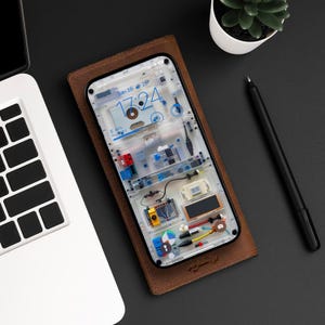 May include: A clear phone case with a brown leather cover. The case has a transparent back that reveals the phone's internal components. The phone's screen displays a digital clock with the date and time. The case has a brown leather cover with the text "Crafted" printed on it.