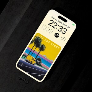 May include: A smartphone screen displaying a digital clock with the time 22:33, a calendar with the date Fri 8, and the text "CITY POP STORY". The background image is a retro-style illustration of a yellow van driving down a road with palm trees and a beach in the distance.