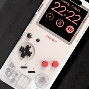 May include: A white Game Boy-style phone case with a black and white Game Boy controller design. The phone screen displays a digital clock with the date "Sunday, 3 March" and the time "22:22".