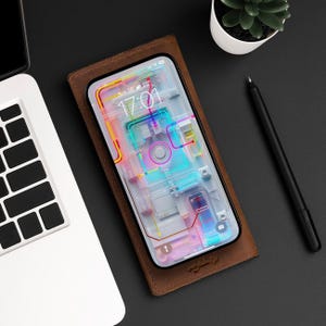 May include: A brown leather phone case with a clear phone inside. The phone screen displays a colorful abstract design with the time 17:01 and the date Sun 26.