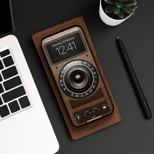 May include: A brown leather phone case with a wood-grain design. The case has a screen displaying a clock with the time 12:41 and the date Saturday, 10 February. The case also has a dial with numbers from 13 to 150.