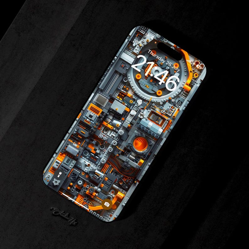 Pu&ograve; includere: Uno smartphone con una custodia personalizzata che presenta un design dettagliato e intricato di ingranaggi, pignoni e altri elementi meccanici in tonalit&agrave; di grigio e arancione. Lo schermo del telefono mostra l'ora, "21:46", e la data, "Gioved&igrave; 25 luglio".