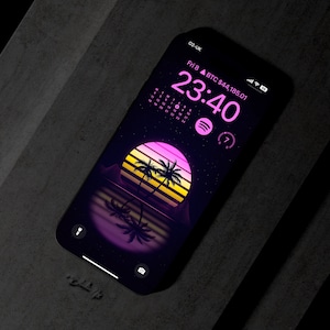 May include: A smartphone with a dark background and a pink and yellow sunset with palm trees. The time is 23:40 and the date is Friday, the 8th. The text "BTC $44,185.01" is displayed on the screen.