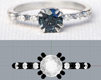 May include: A silver ring featuring a round, teal-colored gemstone as the centerpiece. The band is adorned with small, clear gemstones. The ring is set against a white background, showcasing its elegant design. The ring's design is also shown in a technical drawing.
