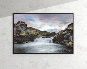 Pode incluir: Uma fotografia de paisagem que mostra uma cachoeira caindo por rochas cobertas de musgo, com um céu nublado ao fundo.