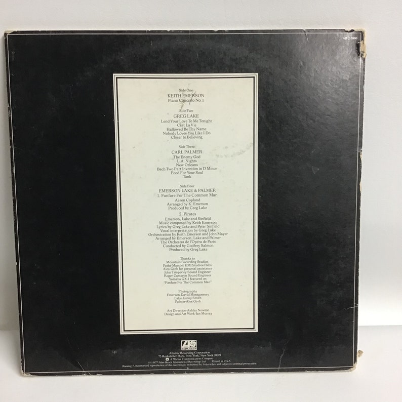 K&ouml;nnte beinhalten: Die R&uuml;ckseite eines Vinyl-Schallplattenalbums f&uuml;r Emerson, Lake & Palmers Album "Fanfare for the Common Man". Das Albumcover ist schwarz mit wei&szlig;em Text, der die Songs auf jeder Seite der Schallplatte auflistet. Der Text enth&auml;lt die Namen der Bandmitglieder Keith Emerson, Greg Lake und Carl Palmer sowie die Songtitel. Das Albumcover enth&auml;lt auch Credits f&uuml;r die Musiker, Produzenten und Toningenieure.