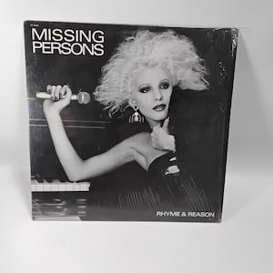May include: Black and white album cover for Missing Persons, featuring a woman with platinum blonde hair holding a microphone. The album title is "Rhyme & Reason". The band's name, "Missing Persons", is printed at the top.