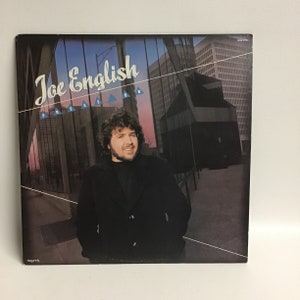 May include: A vinyl record album cover featuring a man with a beard and mustache wearing a black jacket. The album cover is titled "Joe English Press On".