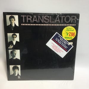 May include: A black vinyl record album cover with the title "Translator" and the text "Heartbeats and Triggers". The cover features four black and white photos of the band members. A sticker on the cover reads "Let Translator Do It For You" and includes the text "Do You Have Trouble Saying What You Mean? Is It Hard For You To Express Your Thoughts And Feelings?"