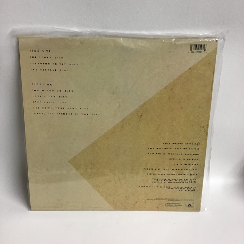 May include: Back cover of a vinyl record with a brown and white design. The record is titled "Mars, The Bringer of War" and features the song titles "The Icons", "Touch and Go", "Love Fling", "Step Aside", "Lay Down Your Guns", and "Mars, The Bringer of War".