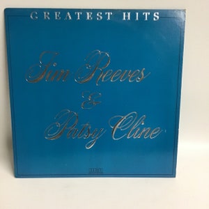 May include: A blue vinyl record album cover with the title "Greatest Hits" and the names "Jim Reeves & Patsy Cline" in silver lettering. The RCA Victor logo is in the bottom right corner.
