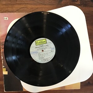 May include: Black vinyl record with a white label. The label has the text "Cotillion" in yellow, "Trilogy" in black, "Emerson, Lake & Palmer" in black, and "SD 9942" in black. The label also has the text "Stereo" in white and "One" in white.