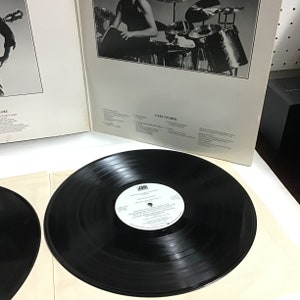 K&ouml;nnte beinhalten: Eine schwarze Schallplatte mit einem wei&szlig;en Label. Das Label tr&auml;gt den Text "CARAVAN OF LOVE" und "KEITH EMERSON" in schwarzer Schrift. Das Label tr&auml;gt auch den Text "ATLANTIC" in einem roten Kreis.