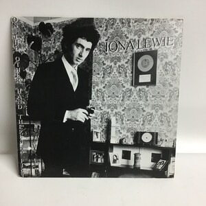 May include: Black and white photo of a man in a suit, holding a cigarette. The photo is on a record album cover with the title "Jona Lewie" and the album title "On The Other Hand There's A Fist" printed on the left side of the cover.