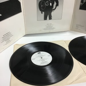 K&ouml;nnte beinhalten: Eine schwarze Schallplatte mit einem wei&szlig;en Etikett mit dem Text "Keith Emerson Piano Concerto No. 2" und "London Philharmonic Orchestra". Die Schallplatte liegt auf einer wei&szlig;en Oberfl&auml;che.