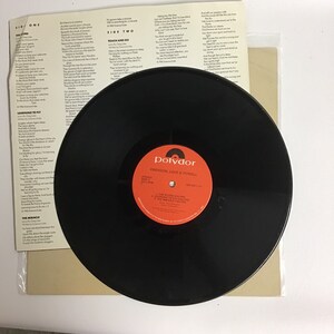 May include: Black vinyl record with a white label. The label has the text "Polydor" in red, "Emerson, Lake & Powell" in black, and the song titles "The  Rondo", "Learning to Fly", and "The Miracle" in black.
