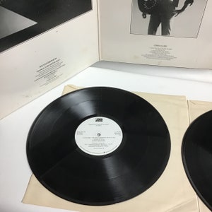 K&ouml;nnte beinhalten: Zwei schwarze Schallplatten mit wei&szlig;en Etiketten. Das Etikett der linken Schallplatte tr&auml;gt den Text "Emerson, Lake & Palmer" und "I  Prepared For The Common Man (20:30)". Das Etikett der rechten Schallplatte tr&auml;gt den Text "Greg Lake" und "I  Loved You So (To The Night)".