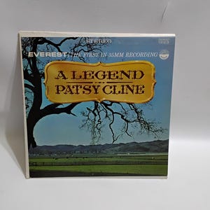 May include: A vintage vinyl record album cover for "A Legend Patsy Cline." The album cover features a landscape scene with a tree, fields, and mountains under a blue sky. The album is labeled "Everest" and "Stereo."