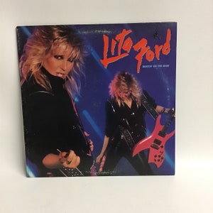 May include: A vinyl record album cover featuring Lita Ford, a female rock musician, with a pink electric guitar. The album title is "Dancin' on the Edge".