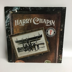 May include: A vintage vinyl record album cover featuring a photo of a group of men in front of a boat with the text "Titanic" on the side. The album cover is brown and has the text "Harry Chapin" in white lettering. The album title is "Dance Band on the Titanic" with a red "T" in a circle.