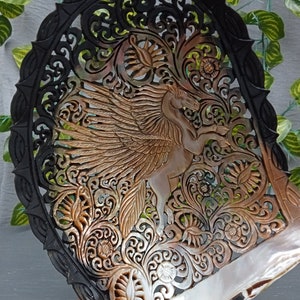 This is a real and natural mother of pearl shell polished and hand carved with wooden stand by a very skilled carving artist in his field. It is very detailed with pegasus design and has high artistic value