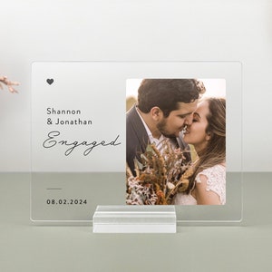 This is a personalized engagement acrylic photo plaque, a perfect keepsake to celebrate a couple's special moment. Perfect for display on a shelf, desk, or nightstand.
