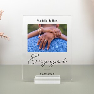 This is a personalized engagement acrylic photo plaque, a perfect keepsake to celebrate a couple's special moment. Perfect for display on a shelf, desk, or nightstand.