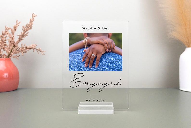 This is a personalized engagement acrylic photo plaque, a perfect keepsake to celebrate a couple's special moment. Perfect for display on a shelf, desk, or nightstand.
