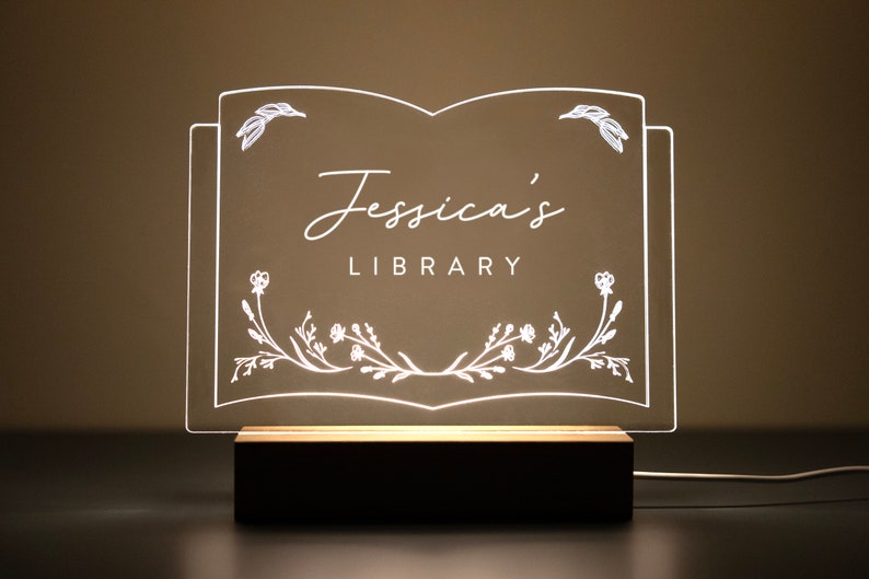 Personalized Library Sign on a clear acrylic book-shaped plaque, featuring floral details and a wood LED base.