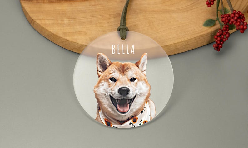 A round acrylic ornament showcasing a smiling dog in cartoon style. The name is written above in a white, playful font. The frosted ornament is attached with a green cord, adding a cheerful touch.
