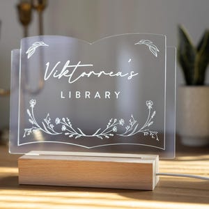 Personalized Library Sign on a clear acrylic book-shaped plaque, featuring floral details and a wood LED base.