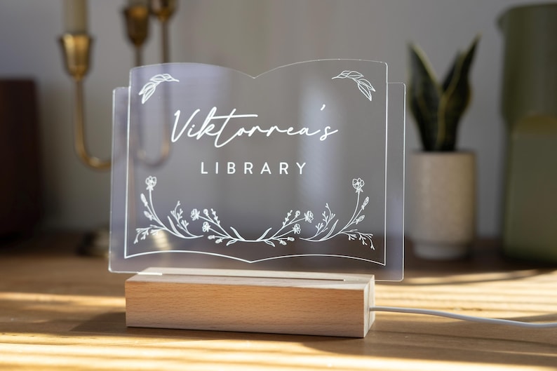 Personalized Library Sign on a clear acrylic book-shaped plaque, featuring floral details and a wood LED base.
