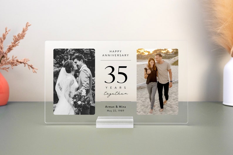 Op de afbeelding: Een transparant acryl fotolijstje met twee zwart-witfoto's en een witte kaart met de tekst "Happy Anniversary 35 Years Together Arman & Mina May 22, 1989".