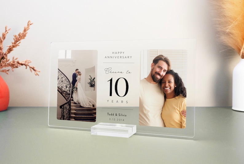 Op de afbeelding: Een helder acryl fotolijst met twee foto's. De linker foto toont een stel op een trap. De rechter foto toont een stel dat lacht. De tekst op het frame luidt "Happy Anniversary Cheers to 10 Years Todd & Silvia 3.12.2014".