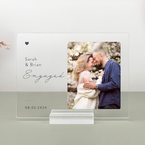 This is a personalized engagement acrylic photo plaque, a perfect keepsake to celebrate a couple's special moment. Perfect for display on a shelf, desk, or nightstand.