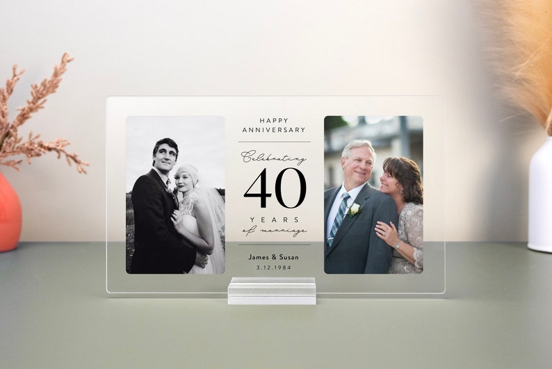 Op de afbeelding: Een helder acryl fotolijst met twee foto's. De linker foto toont een zwart-wit afbeelding van een stel op hun trouwdag. De rechter foto toont een kleuren afbeelding van hetzelfde stel, nu ouder, die naar elkaar lachen. De tekst op de lijst luidt "Happy Anniversary Celebrating 40 Years of Marriage James & Susan 3.12.1984".