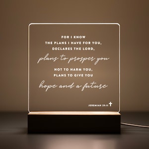 Personalized LED light featuring the uplifting Bible verse from Jeremiah 29:11: "For I know the plans I have for you, declares the Lord, plans to prosper you, not to harm you, plans to give you hope and a future." Engraved on a clear acrylic plaque with a warm wooden base, perfect for home décor, prayer corners, or as a thoughtful Christian gift.